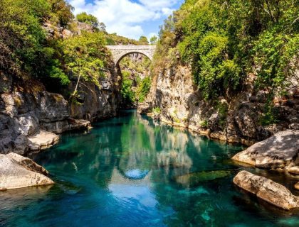 Ancient arch bridge Oluk over the Koprucay river gorge in Koprulu national Park in Turkey. Panoramic scenic view of the canyon and blue stormy mountain river